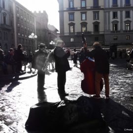 Musicisti in controluce sotto la colonna dell’Abbondanza in piazza della Repubblica.